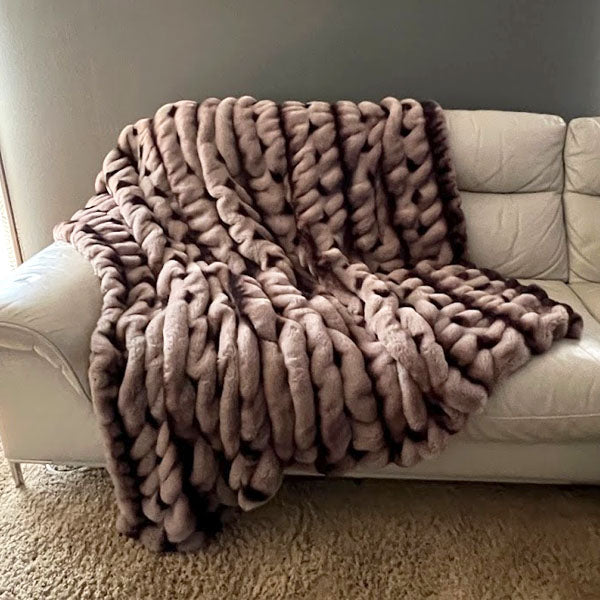 Brown royal Opulence blanket in Taupeful draped over a white sofa against a neutral wall. Handmade in Seattle WA