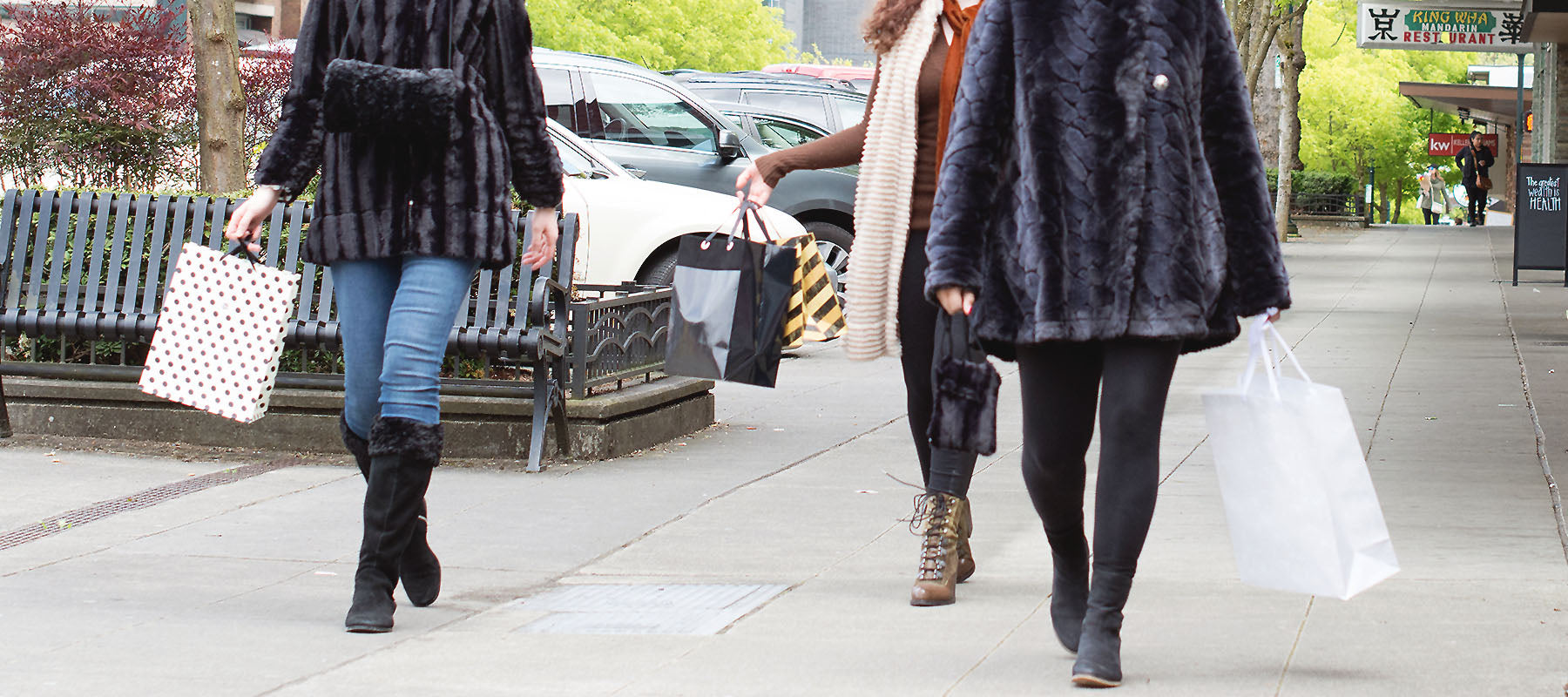 Street View of Women walking in Faux Fur Coats holding Shopping bags