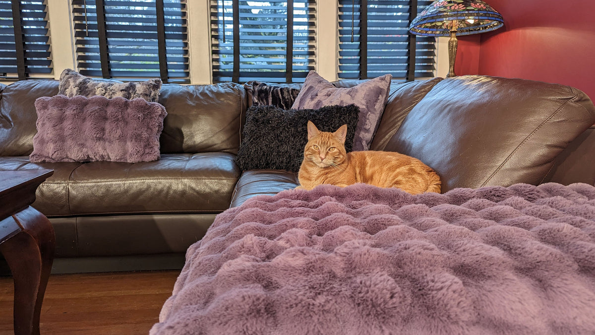 Throw Blanket on brown leather couch in red room in Sugar Plum Enchanted Dreams Faux Fur handmade in Seattle WA USA by Pandemonium Millinery