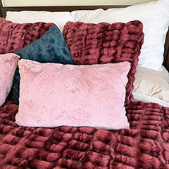 bright pink faux fur bolster pillow on dark pink blanket handmade in Seattle WA by Pandemonium Millinery