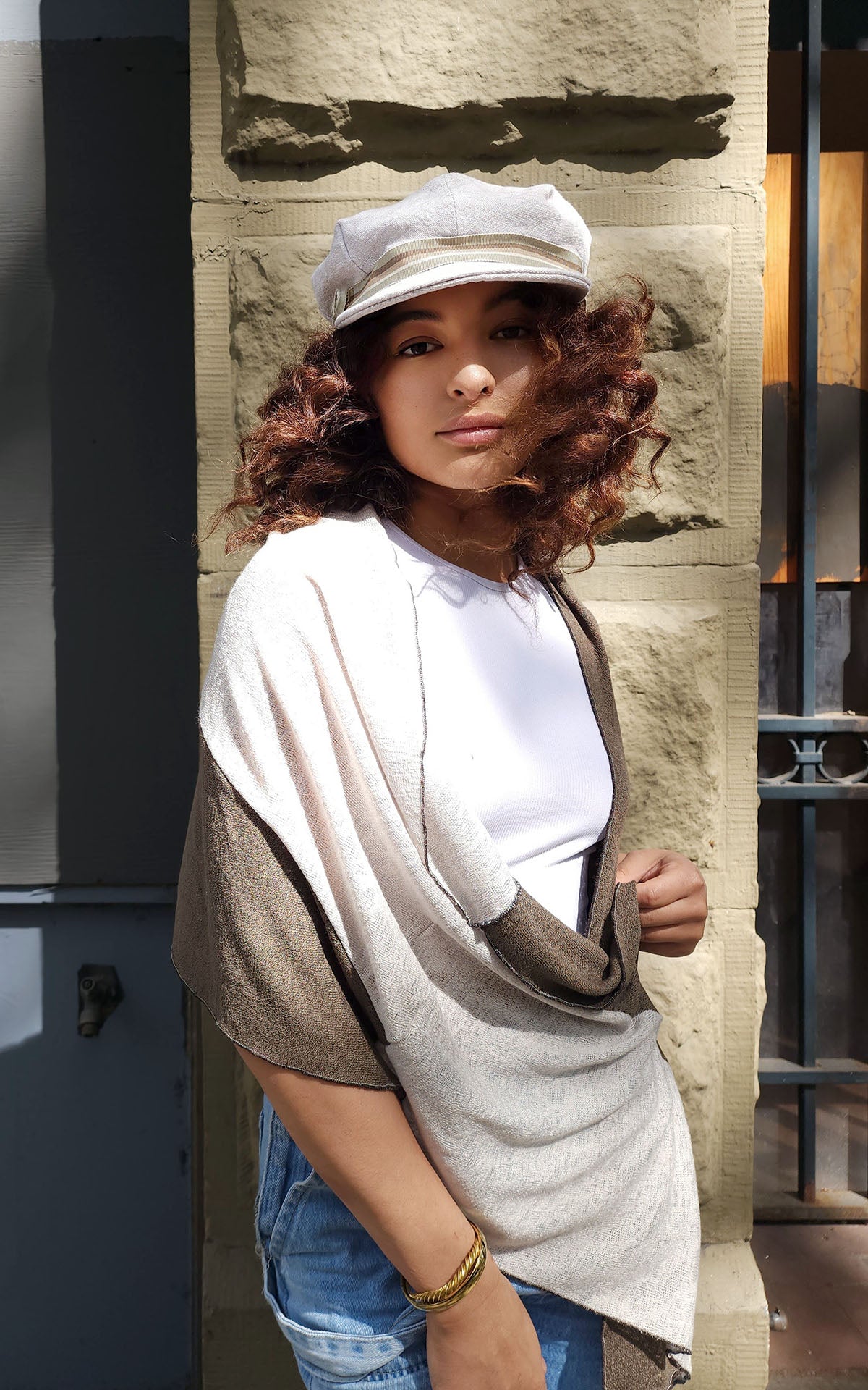 Model wearing Valerie cap hat and Upcycled Motley Scarf in Mezcal and Sandstone on Woman. Large pattern showing open around neck. Handmade in Seattle, WA.