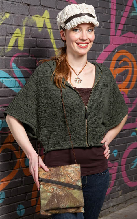 Woman wearing a handmade Prague crossbody travel bag in everglade upholstery fabric against a colorful Seattle mural background. Handcrafted by Pandemonium Millinery.