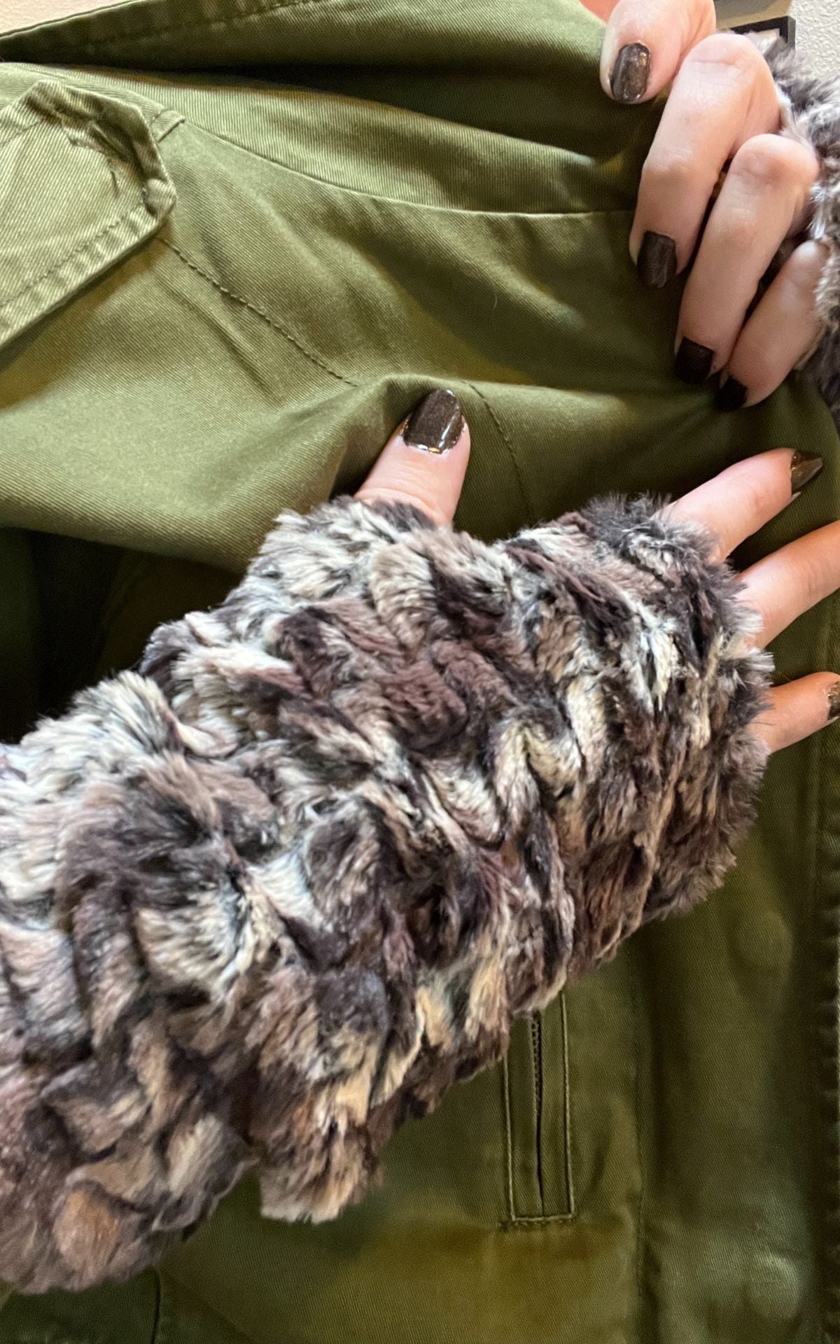 Close up of woman wearing Calico Faux Fur Fingerless Gloves and a green jacket. Made in Seattle, WA, USA. Pandemonium Seattle.&#39;