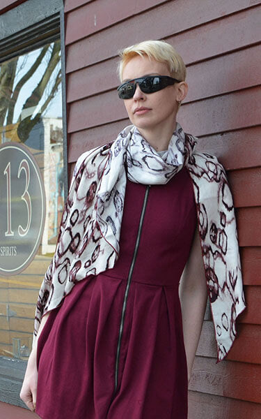 Women Leaning against red wall wearing  large Handkerchief Scarf, Wrap | Crystal Raindrops in Mahogany, ring pattern in dark rust and off-white | Handmade in Seattle WA | Pandemonium Millinery