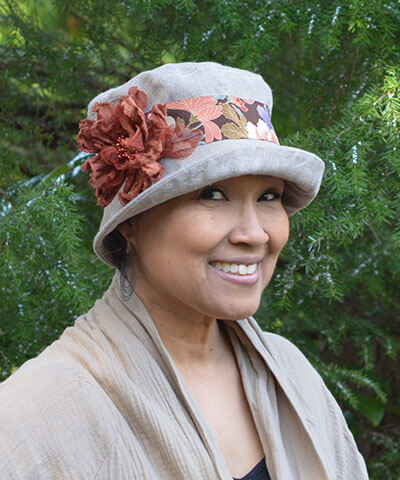 Model wearing Molly Bucket Style Hat Natural Linen with Kimono Silk Floral Band with Large Rust Flower Brooch | Pandemonium Millinery | Handmade in Seattle WA