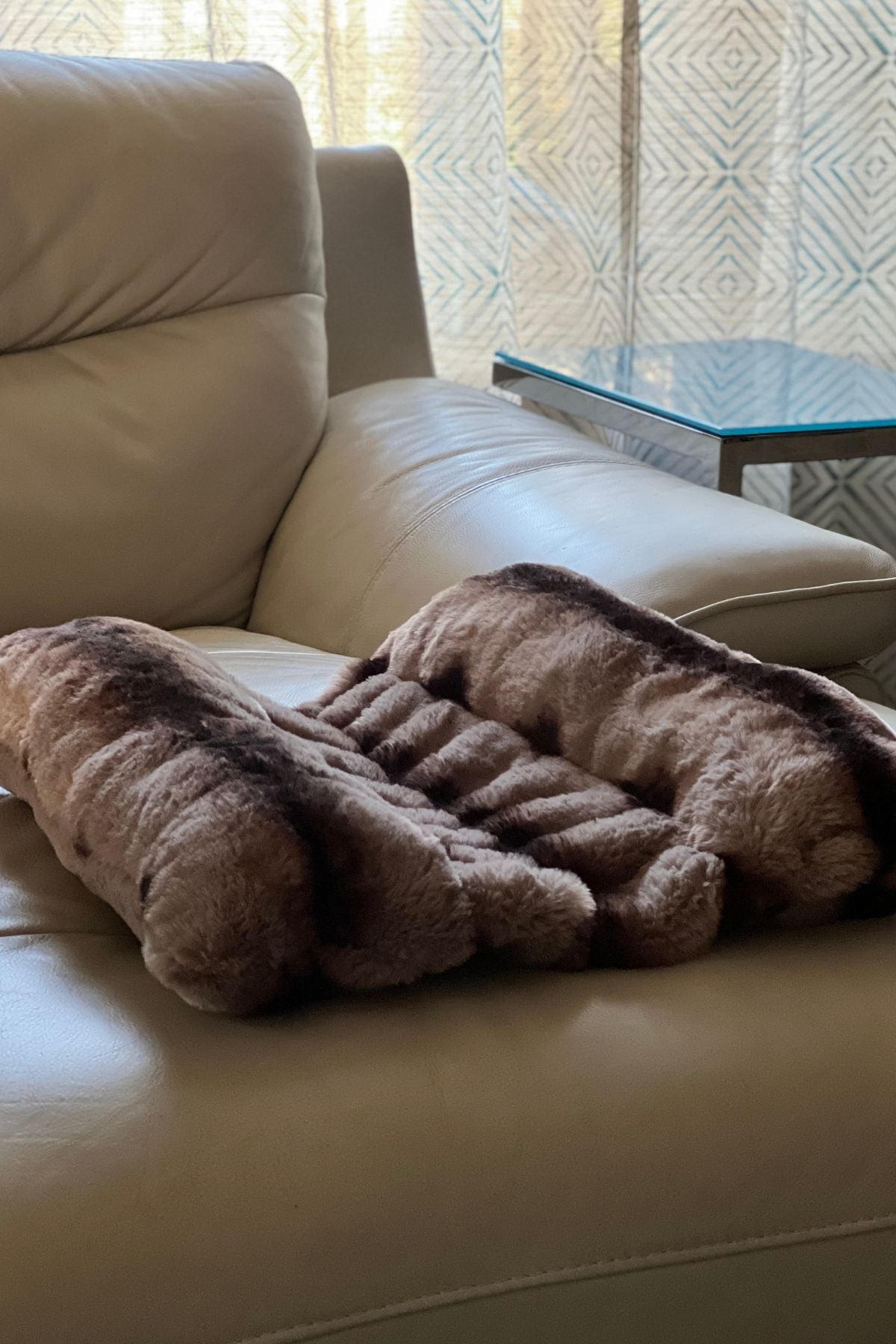 Pet Bed in Royal Opulence color Taupeful, laying across a cream-color leather couch. Handmade in Seattle, WA.