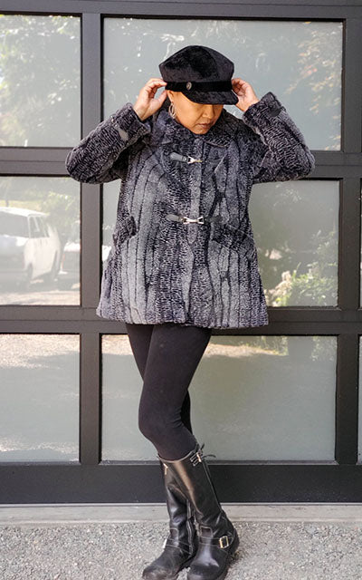 Glass door background with a model wearing a Valerie Cap Style hat in Pebbles in Black with Black Velvet Band and Button handmade in Seattle, WA USA by Pandemonium Millinery.