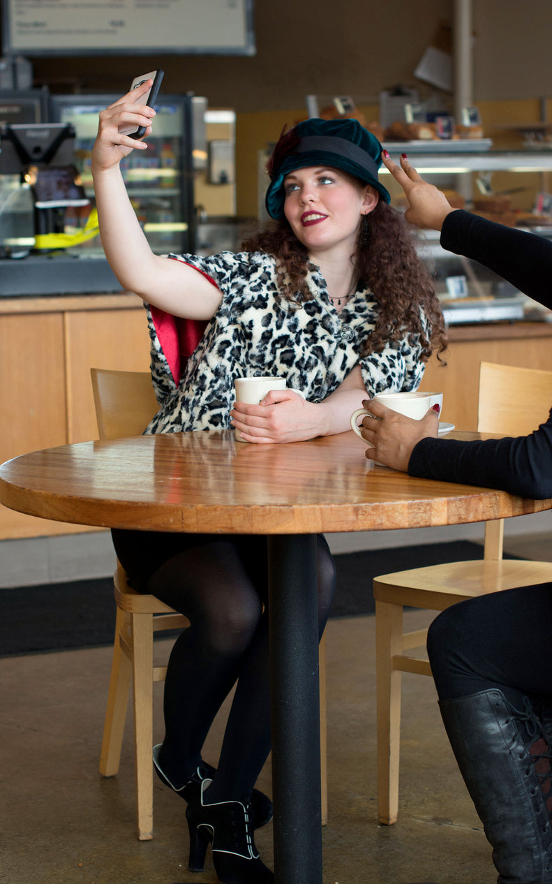 Model in Café wearing Opera Cape | White Jaguar Faux Fur | Handmade by Pandemonium Millinery | Seattle WA USA
