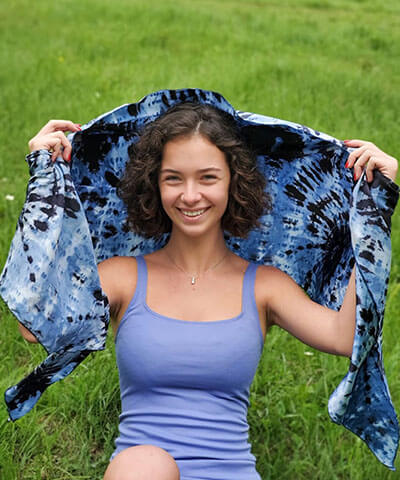 Women’s sitting on the grass holding a scarf over her head, Large Handkerchief Scarf, Wrap | Egyptian Mirage, black, Blues, and ivory tie-dye | Handmade in Seattle WA | Pandemonium Millinery