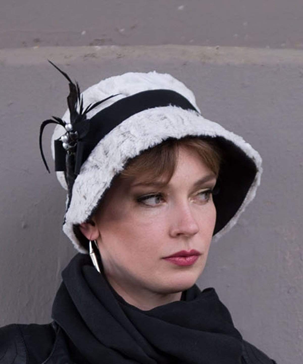 Woman wearing Abigail Hat in Winter’s Frost White Luxury Faux Fur with Black Faux Suede under rim. Trimmed with Black Grosgrain Band and Feathers| Handmade in Seattle WA| Pandemonium Millinery 