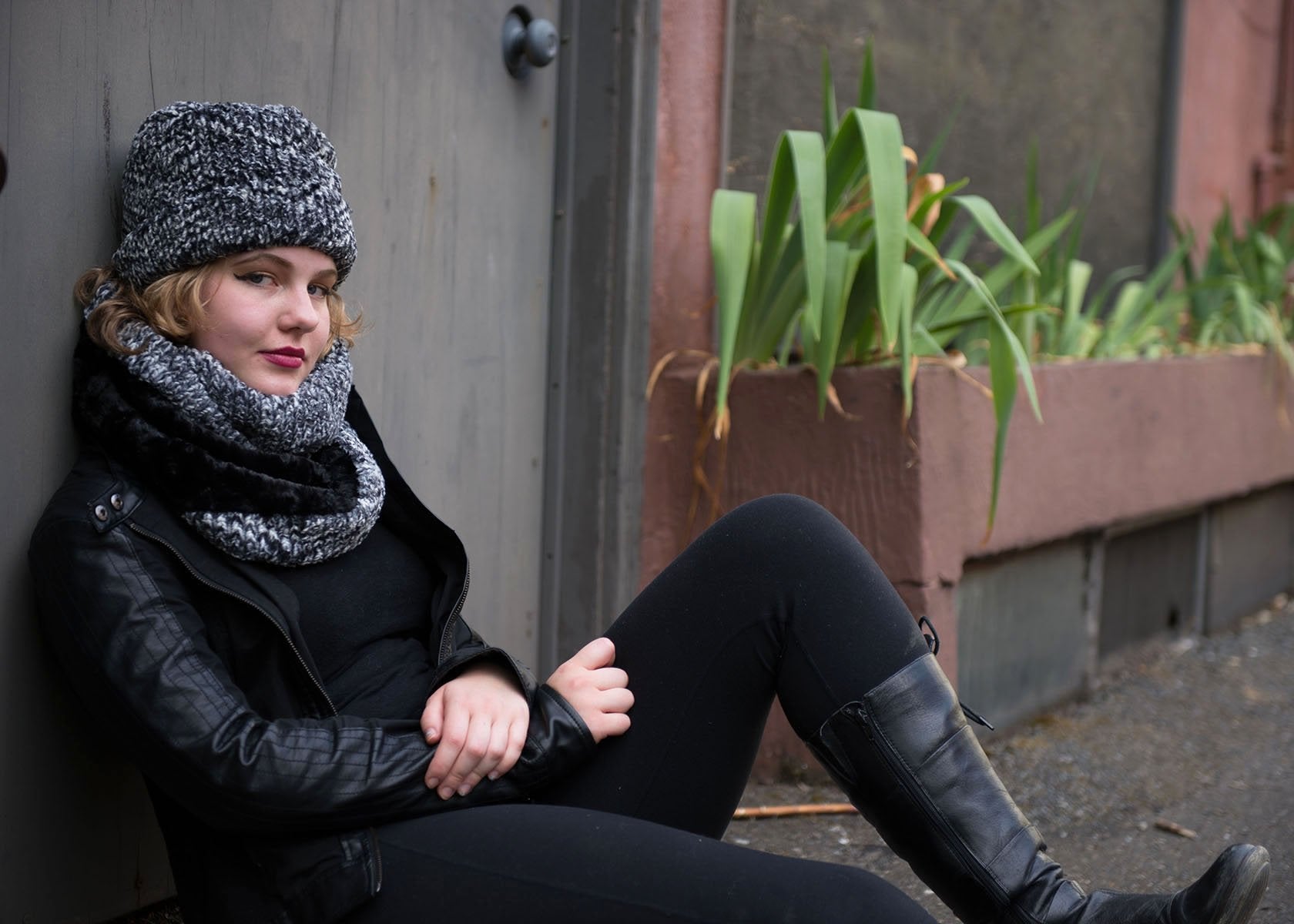 Women's Cuffed Pillbox on model sitting against a wall| Cozy Cable Black and White Faux Fur with matching Neck Cowl | Handmade USA by Pandemonium Seattle