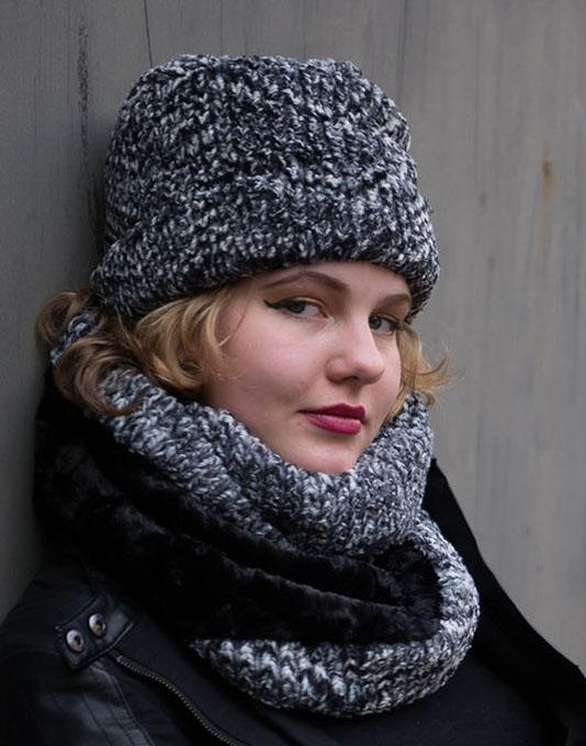 Women's Cuffed Pillbox on model sitting against a wall| Cozy Cable Black and White Faux Fur with matching Neck Cowl | Handmade USA by Pandemonium Seattle