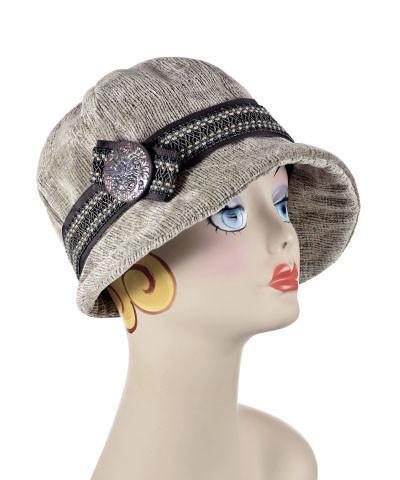 Product Shot of the Grace Cloche Hat in Bongo Beige upholstery fabric. This example is decorated with a grosgrain band and a large chocolate button. Handmade in Seattle, WA, USA by Pandemonium Seattle.