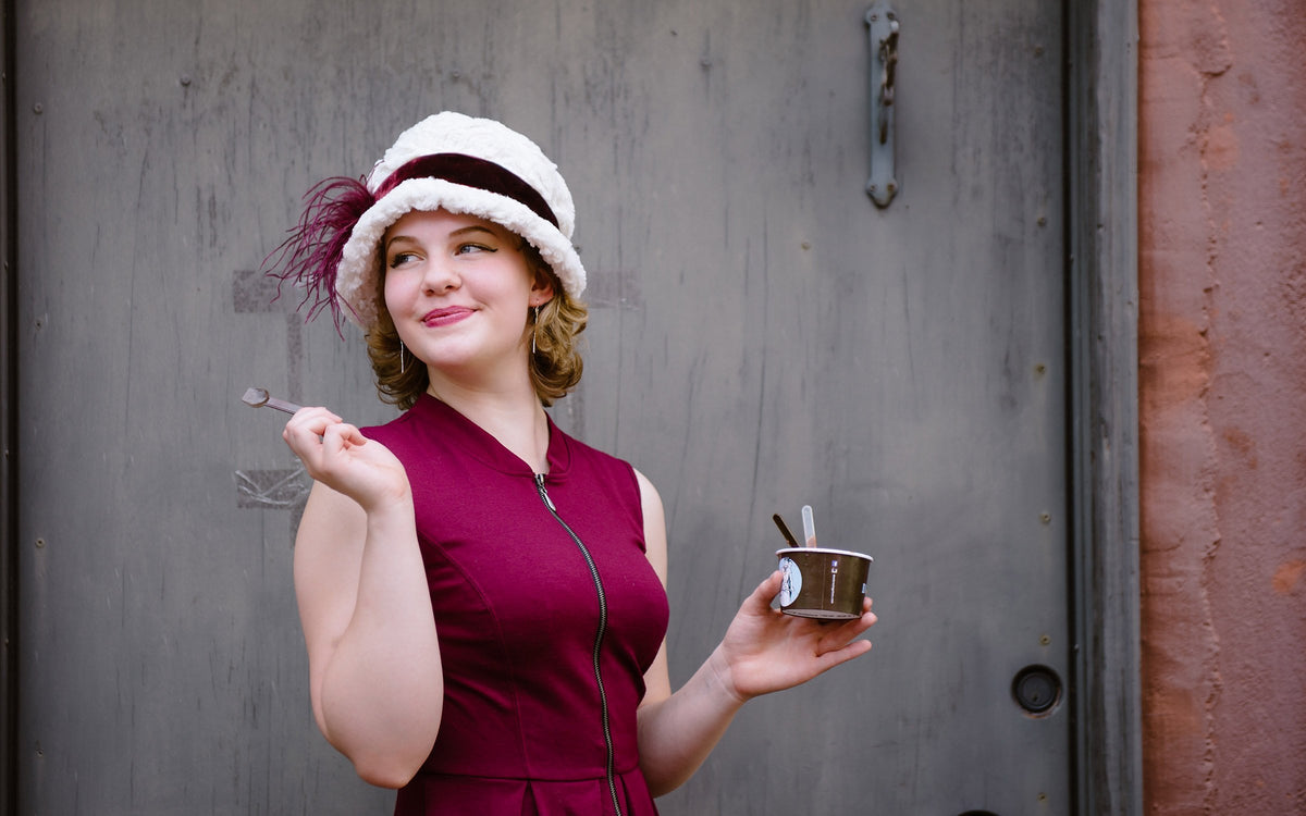 Smiling woman features Grace 1920s Cloche Style Hat in Cuddly Faux Fur Ivory featuring Midori Velvet Crimson Band with Burgundy Ostrich Brooch | Handmade By Pandemonium Seattle | Seattle WA USA