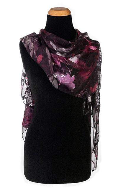 Women against rust wall wearing Large Handkerchief Scarf, Wrap in hand-painted silk | Garden Path in Tiger Lily black, green, rust, yellow, and Gray | Handmade in Seattle WA | Pandemonium Millinery