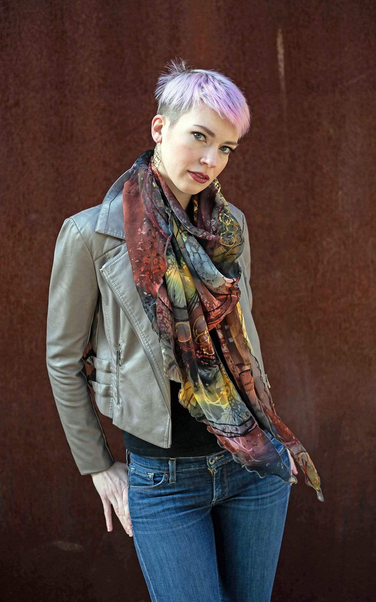 Women against rust wall wearing Large Handkerchief Scarf, Wrap in hand-painted silk | Garden Path in Tiger Lily black, green, rust, yellow, and Gray | Handmade in Seattle WA | Pandemonium Millinery
