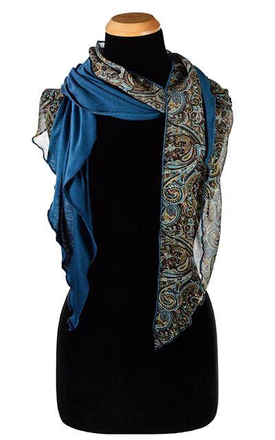Women Leaning against a brick wall wearing Ana 1920’s cloche style hat and matching  Handkerchief Scarf, Wrap | Peacock Paisley Chiffon in blue, greens, and browns | Handmade in Seattle WA | Pandemonium Millinery