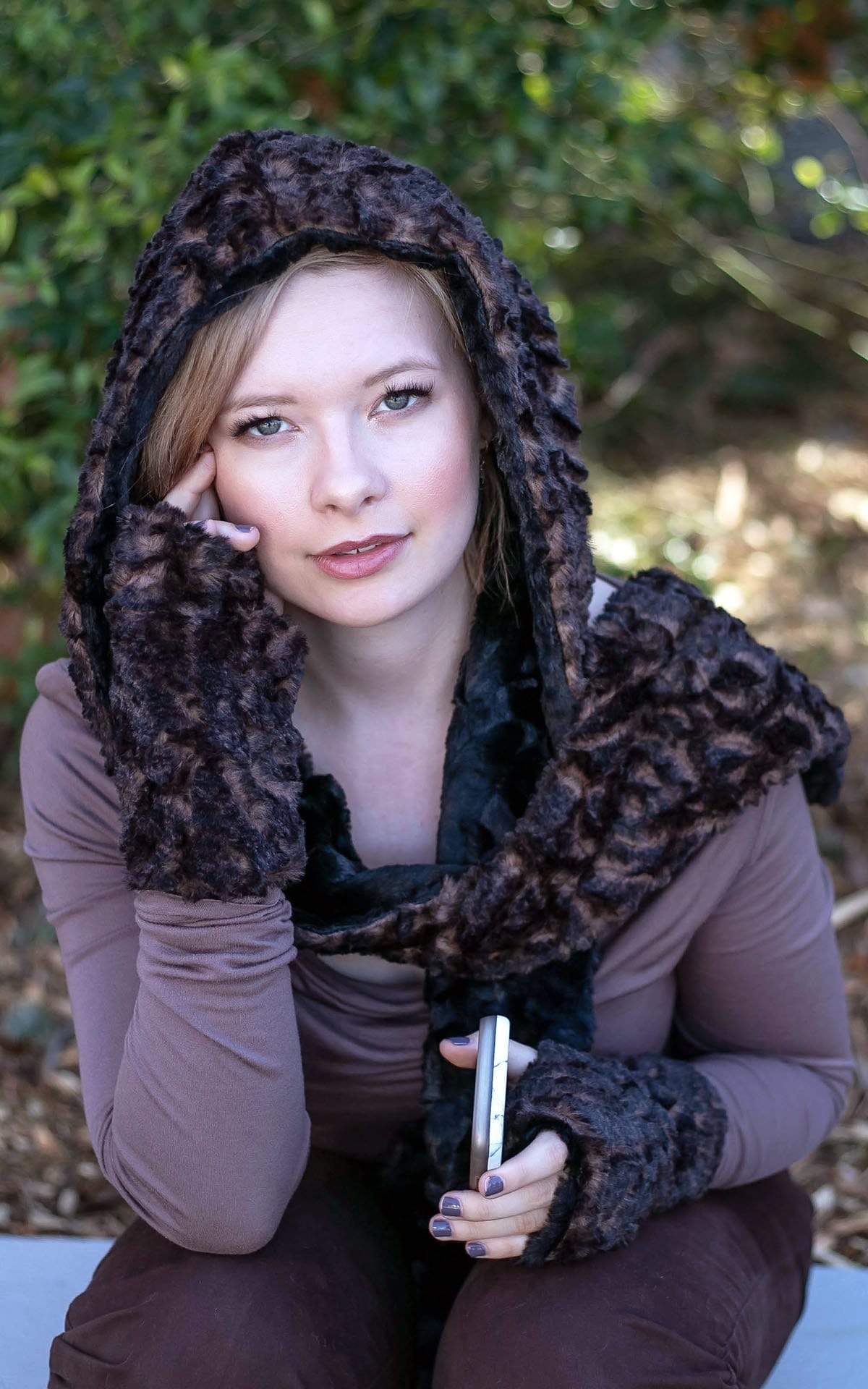 Model sitting in park wearing Fingerless Gloves and matching  Two-Tone Hooded Scarf | Vintage Rose, black and brown Cuddly Fur in Black Faux Fur | Handmade in Seattle WA | Pandemonium Millinery