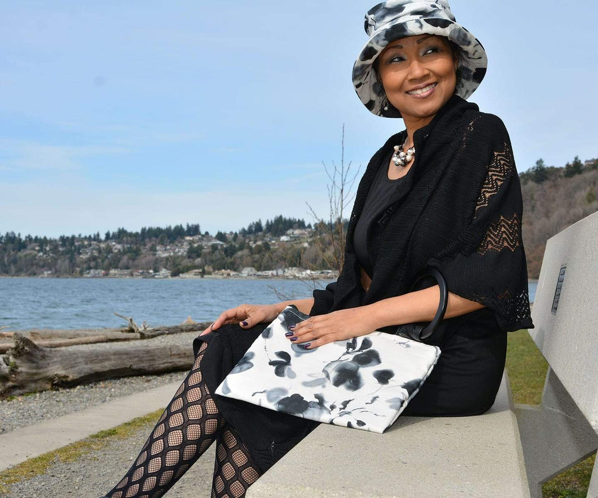 woman wearing matching bag with Krystyne Bucket Hat in Black and White Floral Linen Handmade in Seattle WA by Pandemonium Millinery USA