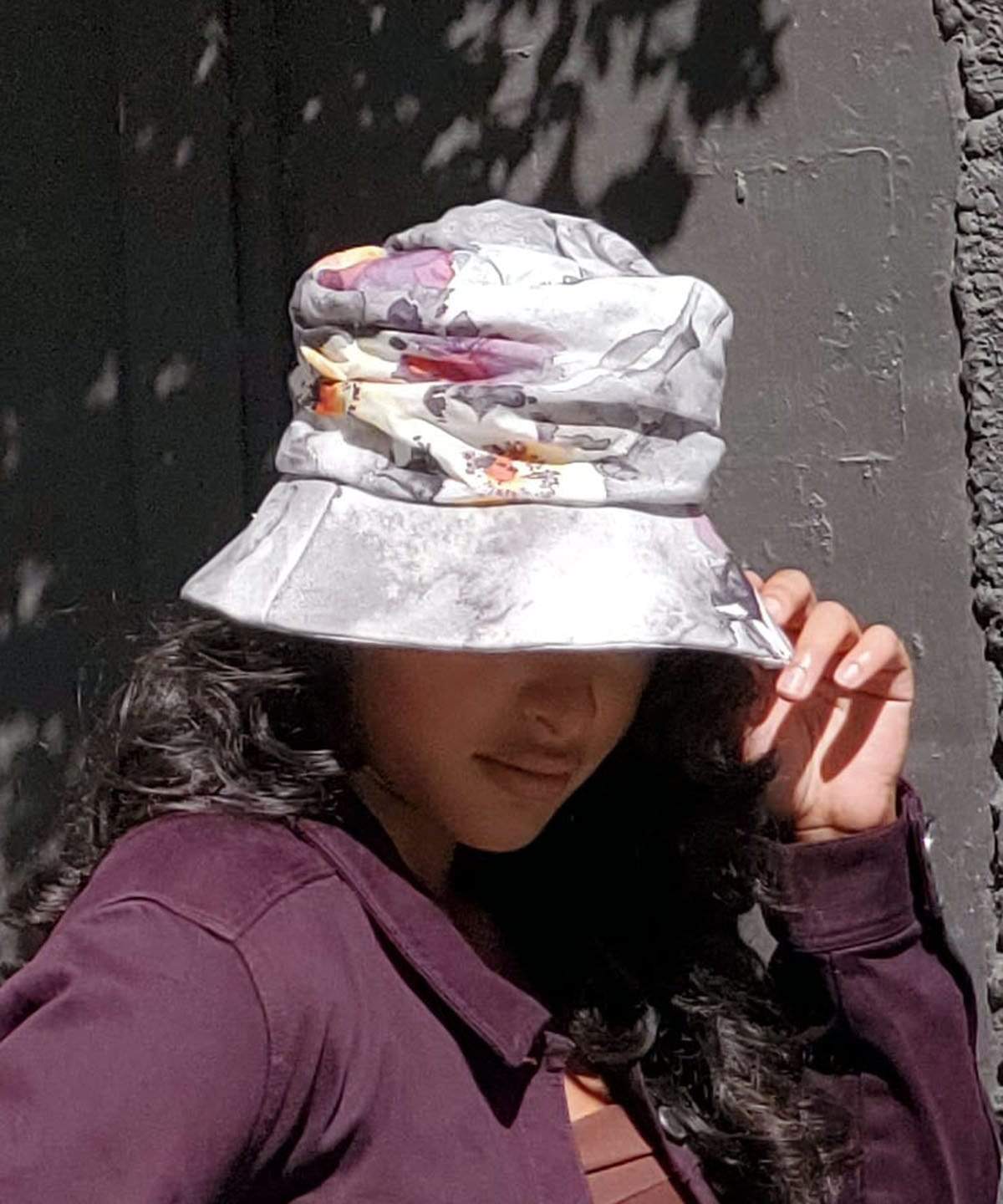 woman holding brim down on Krystyne Bucket Hat in Colorful Floral Linen Handmade in Seattle WA by Pandemonium Millinery USA