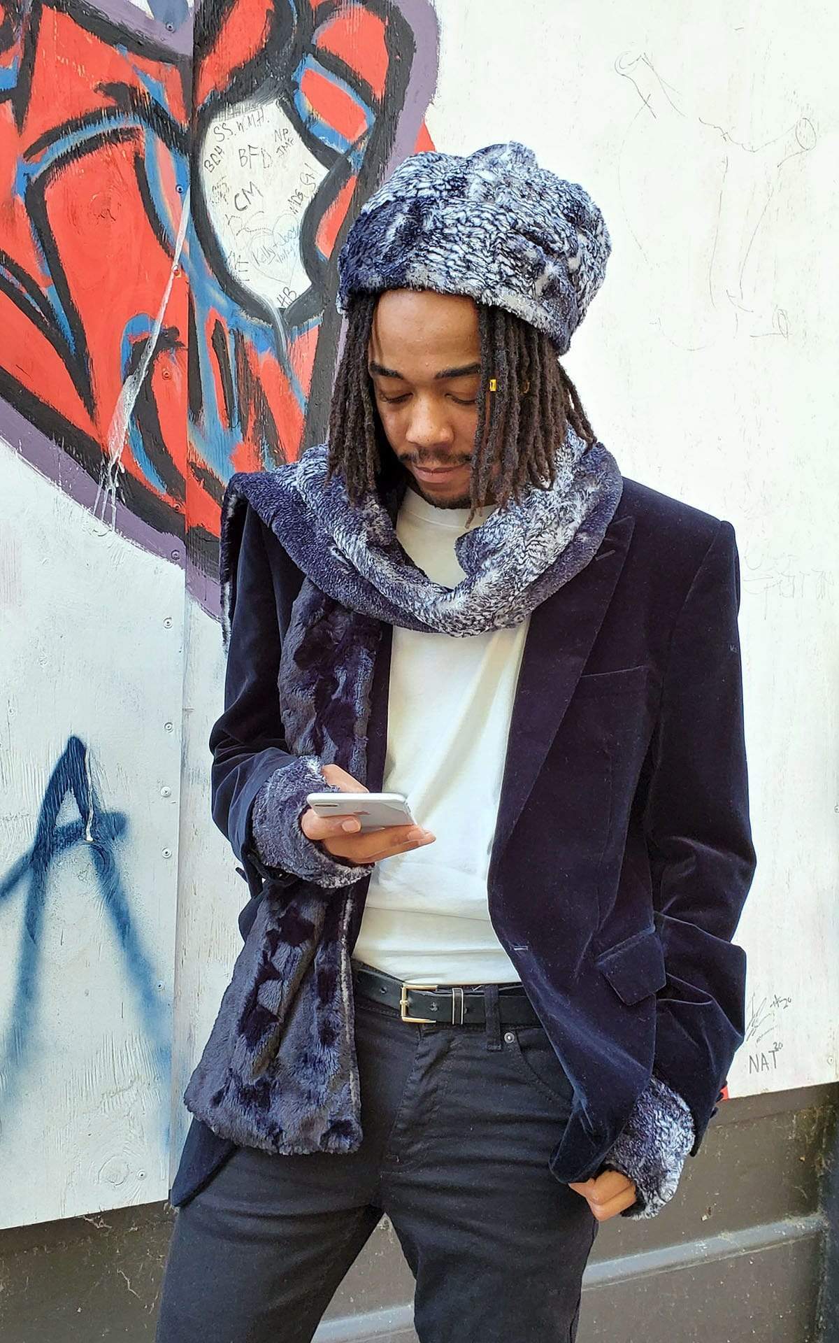 Male Model wearing beanie matching hat and  Classic Scarf against graffiti wall looking at phone | Black Mamba animal snake print with Cuddly Black Faux Fur | Handmade by Pandemonium Millinery Seattle, WA USA