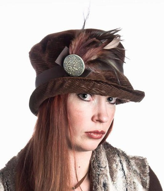 Women wearing Molly Bucket Style Hat Cohen in Chocolate Upholstery with a Chocolate Grosgrain Band featuring Natural and Mauve Feather Brooch with Hand painted Button | Handmade By Pandemonium Millinery | Seattle WA