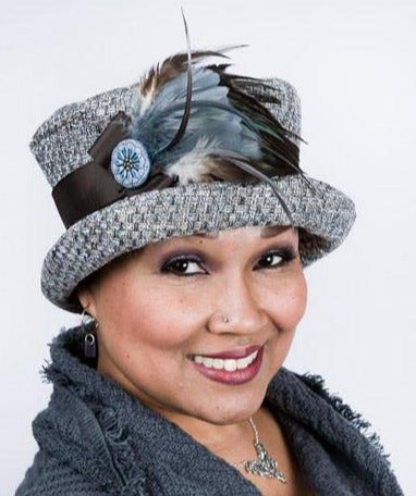 Woman wearing Molly Bucket Style Hat in Frozen Tundra Upholstery fabric  with  Blue Steel and Natural feather Brooch featuring a hand painted Blue Button | Handmade By Pandemonium Millinery in Seattle WA USA