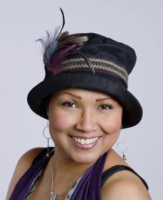 Model is wearing Molly Hat Linen in Black with Braided Band and  Steel and Plum feathers by Pandemonium Milllinery. Handmade in Seattle, WA.
