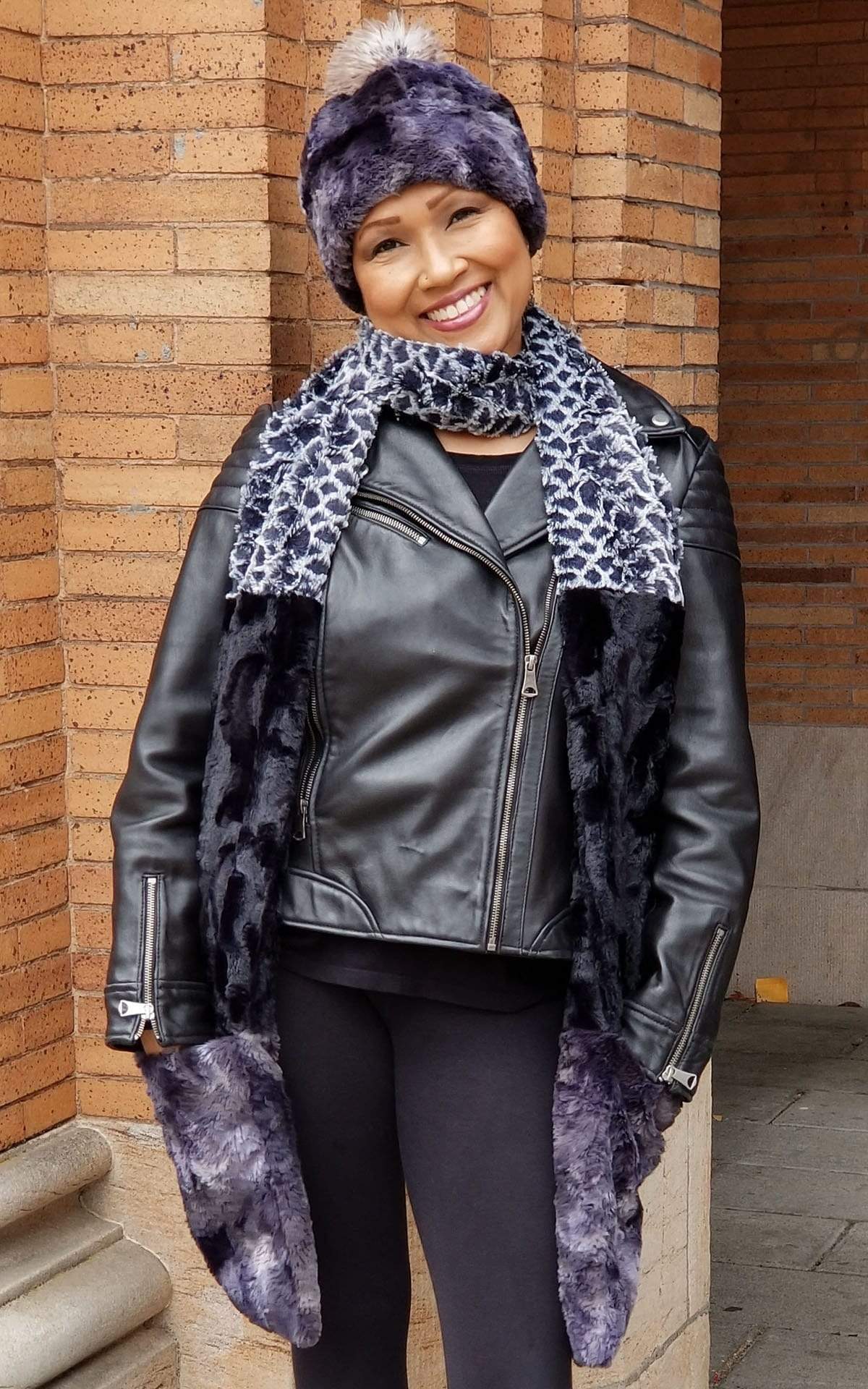 Women in front of Glass and brick wall wearing Beanie hat with Pom Pom with matching  the Color Tri-Color Pocket Scarf | Snow Owl, Cuddly Black, and Highland in Skye a  combo of blacks grays, and blue Faux Fur | Handmade in Seattle WA Pandemonium Millinery