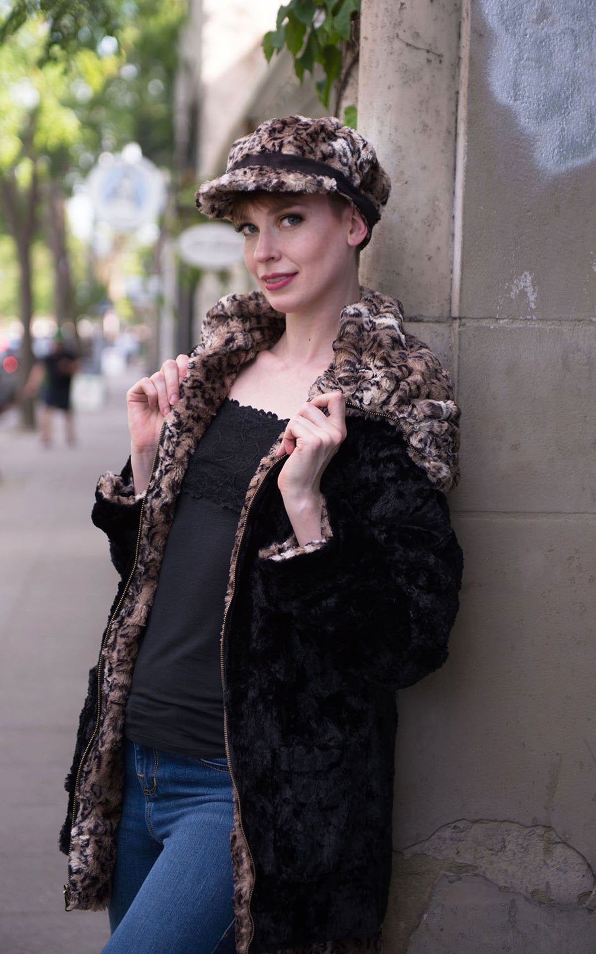 Model, leaning on a wall, wearing Valerie Cap Carpathian Lynx with Faux Suede Black Band by Pandemonium Millinery. Handmade in Seattle, WA USA.