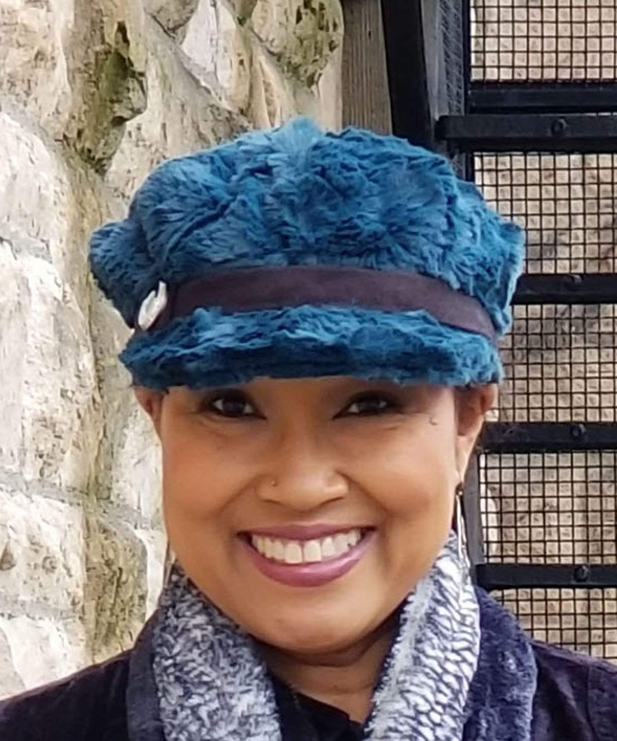 Front view of Model wearing a Valerie Cap Style hat in Peacock Pond Faux Fur with Black Faux Suede band and glass button trim By Pandemonium Millinery. Hand made in Seattle, WA USA.
