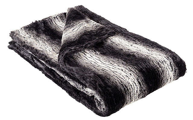 Faux fur throw in Smouldering Sequoia draped over back of black leather sofa. Made in Seattle, WA, USA. Pandemonium Millinery.