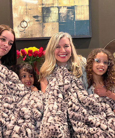  A family bundled up in a Luxury Faux Fur  Throw in Snow Leopard From Royal Opulence Collection Made in Seattle