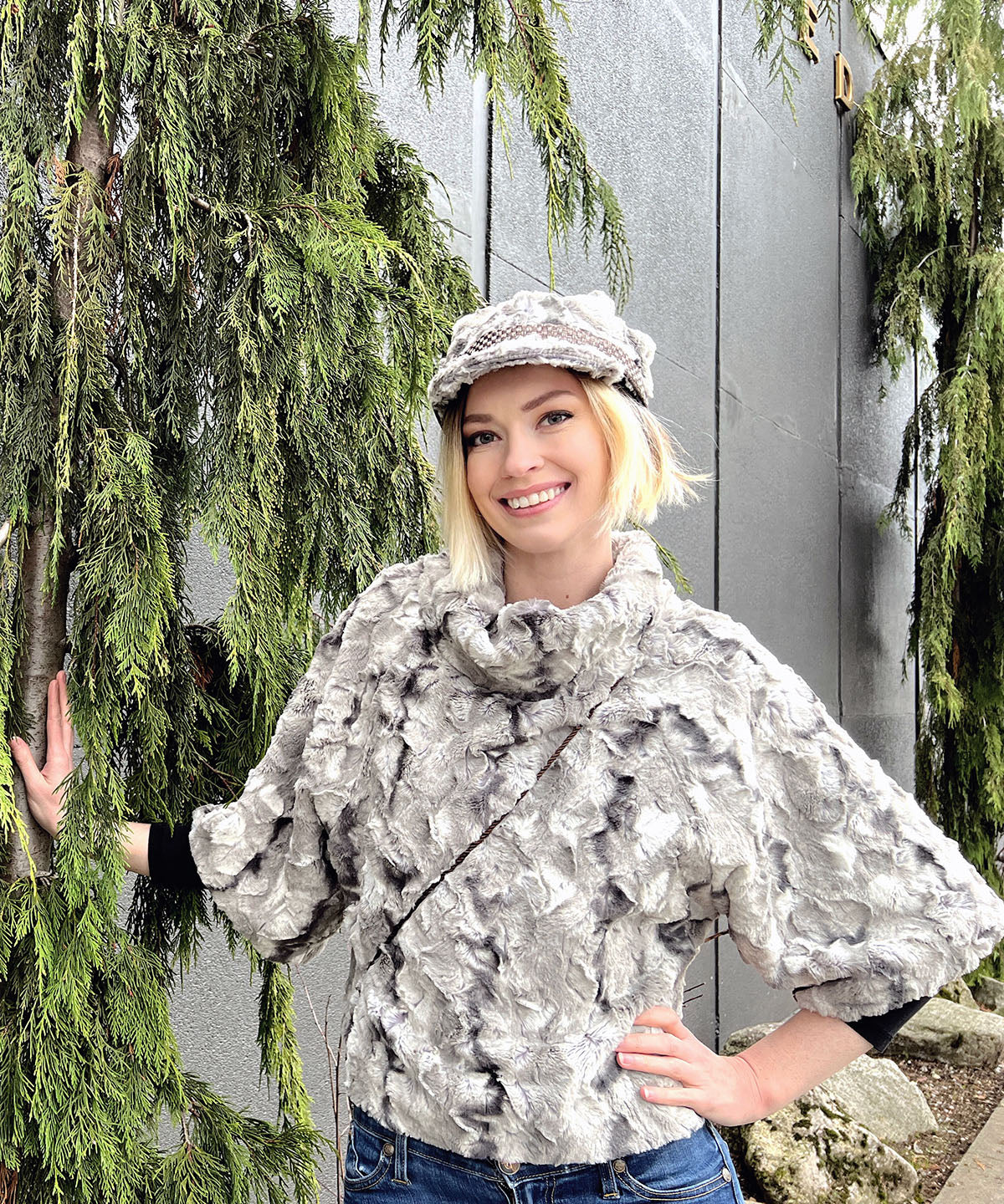 Model leaning on Tree, wearing White Water Faux Fur Valerie Cap style hat and matching Sweater Top.  Handmade in Seattle, WA by Pandemonium Millinery.